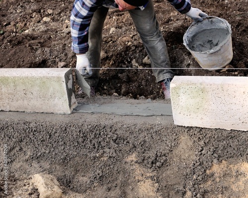 Photo: Construction site - Worker laying concrete curbs Construction site - Worker laying concrete curbs