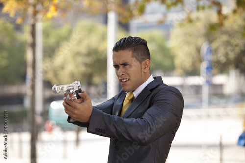 Photo: Powerful security businessman aiming a gun Powerful security businessman aiming a gun