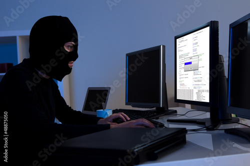 Photo: Hacker downloading information off a computer Hacker downloading information off a computer