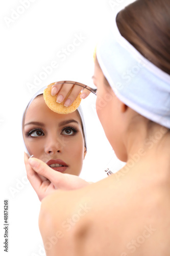 Photo: Young woman cleansing her face, isolated on white Young woman cleansing her face, isolated on white