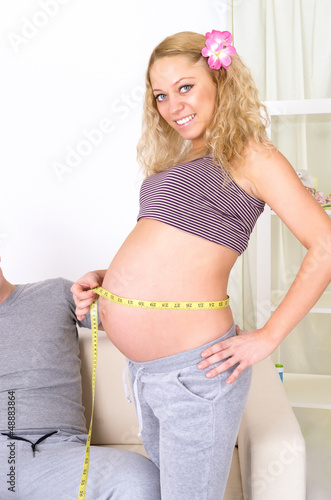 Photo: Beautiful pregnant woman measuring her belly Beautiful pregnant woman measuring her belly