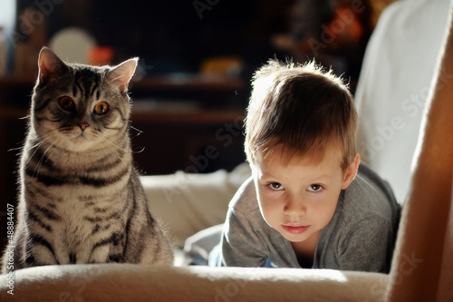Photo: in a room on the sofa lay a boy with black cat in a room on the sofa lay a boy with black cat