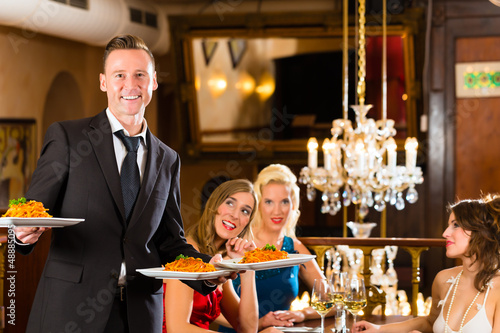Photo: Friends in restaurant, waiter served the dinner Friends in restaurant, waiter served the dinner