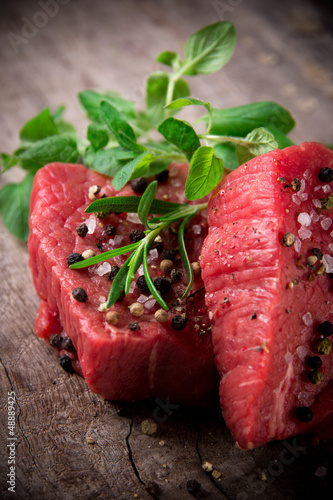 Photo: Raw beef steaks on wooden table Raw beef steaks on wooden table