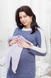 pregnant woman holds a children's romper suit