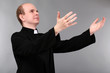 Young priest on gray background