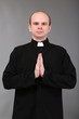 Young priest on gray background