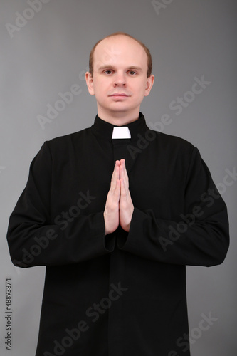 Photo: Young priest on gray background Young priest on gray background