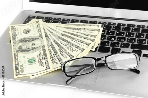 Photo: Money with glasses on laptop close-up Money with glasses on laptop close-up