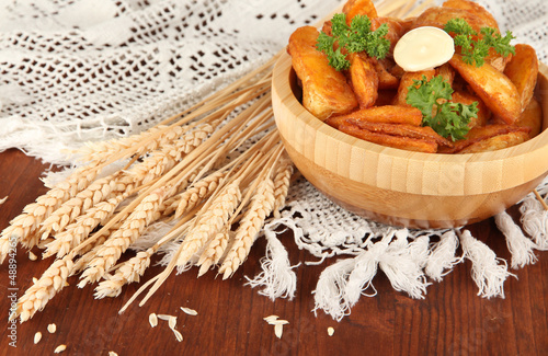 Photo: Appetizing village potatoes in bowl on wooden table close-up Appetizing village potatoes in bowl on wooden table close-up