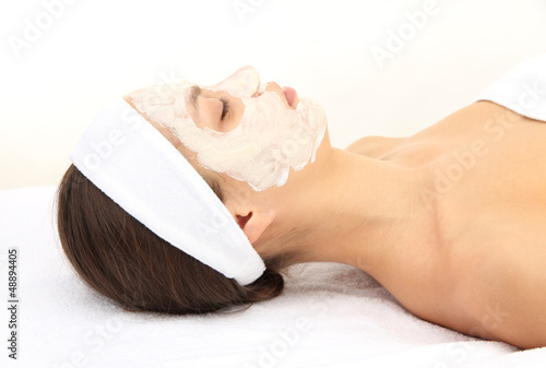 Photo: Young woman with clay facial mask, isolated on white Young woman with clay facial mask, isolated on white