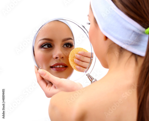 Photo: Young woman cleansing her face, isolated on white Young woman cleansing her face, isolated on white