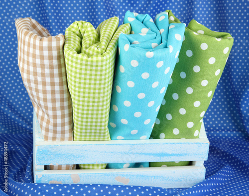 Photo: Color mottled fabrics in basket on blue fabric background Color mottled fabrics in basket on blue fabric background