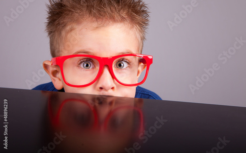 Photo: Five years old little cute boy hiding behind a table Five years old little cute boy hiding behind a table