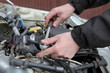 Mechanic servicing engine, ratchet and spark plug
