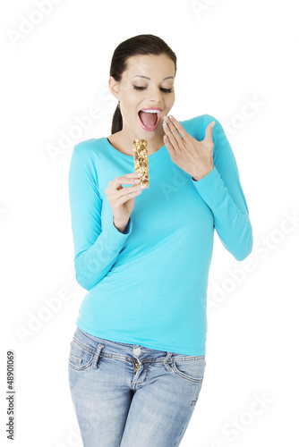 Photo: Young woman eating Cereal candy bar Young woman eating Cereal candy bar