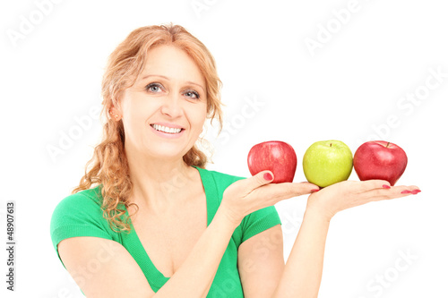 Photo: Mature beautiful woman sitting and holding three apples Mature beautiful woman sitting and holding three apples