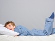 Playful little boy wearing blue pyjamas in bed