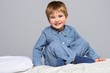 Playful little boy wearing blue pyjamas in bed