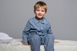 Foto: Playful little boy wearing blue pyjamas in bed Playful little boy wearing blue pyjamas in bed