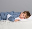 Playful little boy wearing blue pyjamas in bed