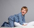 Photo: Playful little boy wearing blue pyjamas in bed Playful little boy wearing blue pyjamas in bed