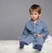 Disappointed little boy in blue pyjamas on bed