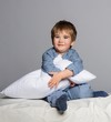 Playful little boy wearing blue pyjamas in bed