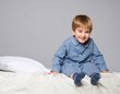 Playful little boy wearing blue pyjamas in bed