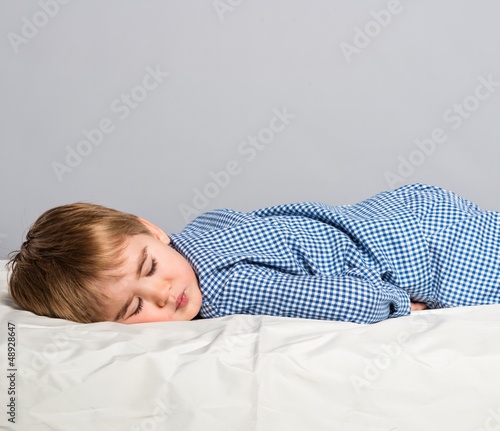 Photo: Little boy in blue pyjamas sleeping in bed Little boy in blue pyjamas sleeping in bed