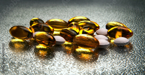 Photo: Closeup of vitamin E and D capsules on metallic background Closeup of vitamin E and D capsules on metallic background