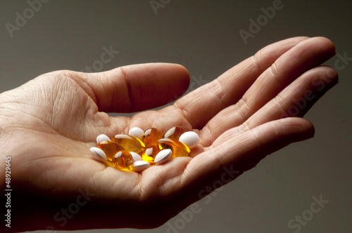 Photo: Closeup of hand holding vitamin E and vitamin D capsules Closeup of hand holding vitamin E and vitamin D capsules
