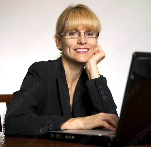 Photo: Happy, smiling female executive office with hands on computer Happy, smiling female executive office with hands on computer