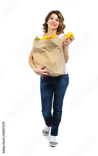 Photo: Young girl with fruits in paper bag isolated on white Young girl with fruits in paper bag isolated on white