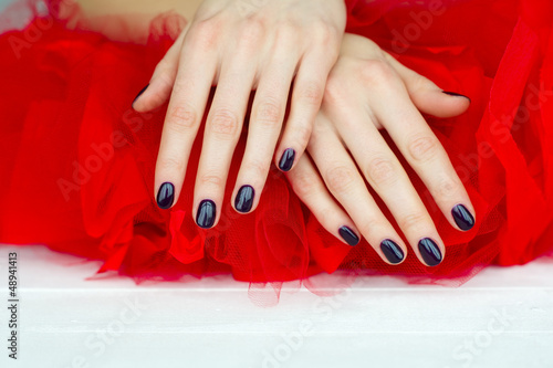 Photo: Closeup dark manicure on red Closeup dark manicure on red
