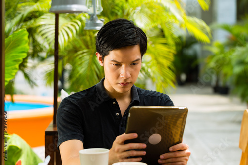 Photo: Asian man is sitting in a bar or cafe outdoor Asian man is sitting in a bar or cafe outdoor