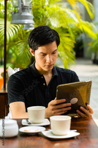 Photo: Asian man is sitting in a bar or cafe outdoor Asian man is sitting in a bar or cafe outdoor