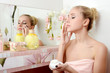 The beautiful woman blonde puts on face a cream