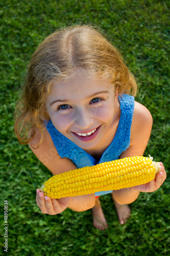 Photo: Healthy food - lovely girl eating corn on the cob Healthy food - lovely girl eating corn on the cob