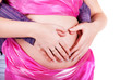 young couple making heart shape with arms on the belly of expect