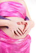 young couple making heart shape with arms on the belly of expect