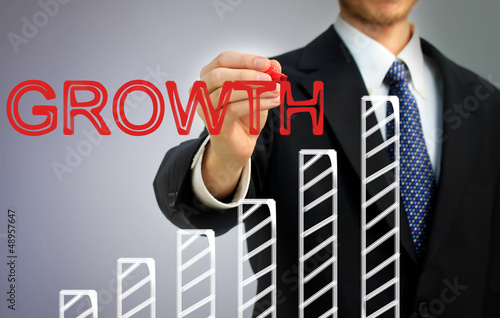 Photo: Businessman writing growth over a bar graph Businessman writing growth over a bar graph