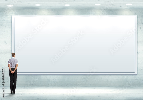 Photo: Business person standing near a blank billboard Business person standing near a blank billboard