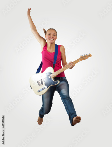 Photo: young woman playing on electro guitar and jumping young woman playing on electro guitar and jumping