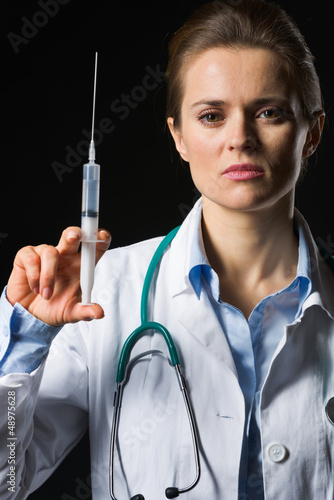Photo: Medical doctor woman holding syringe isolated on black Medical doctor woman holding syringe isolated on black