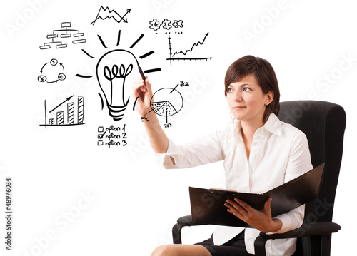 Photo: Young business woman drawing light bulb with various diagrams an Young business woman drawing light bulb with various diagrams an