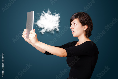 Photo: Young woman looking at modern tablet with abstract cloud Young woman looking at modern tablet with abstract cloud