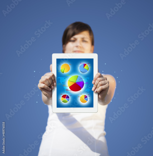 Photo: Young woman looking at modern tablet with abstract light and var Young woman looking at modern tablet with abstract light and var