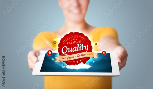 Photo: woman holding tablet with red quality label in clouds woman holding tablet with red quality label in clouds