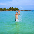 handsome boy enjoys sputtering with his hand in the tropical oce